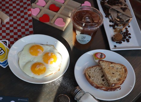Sunny-side-up eggs, toast, and iced coffee at Bobby's Breakfast Cafe & Bar in Toronto
