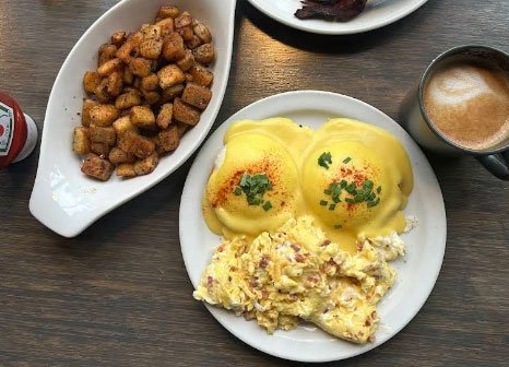 Eggs Benedict with scrambled eggs, home fries, and coffee at Bobby's Breakfast Cafe & Bar in Toronto